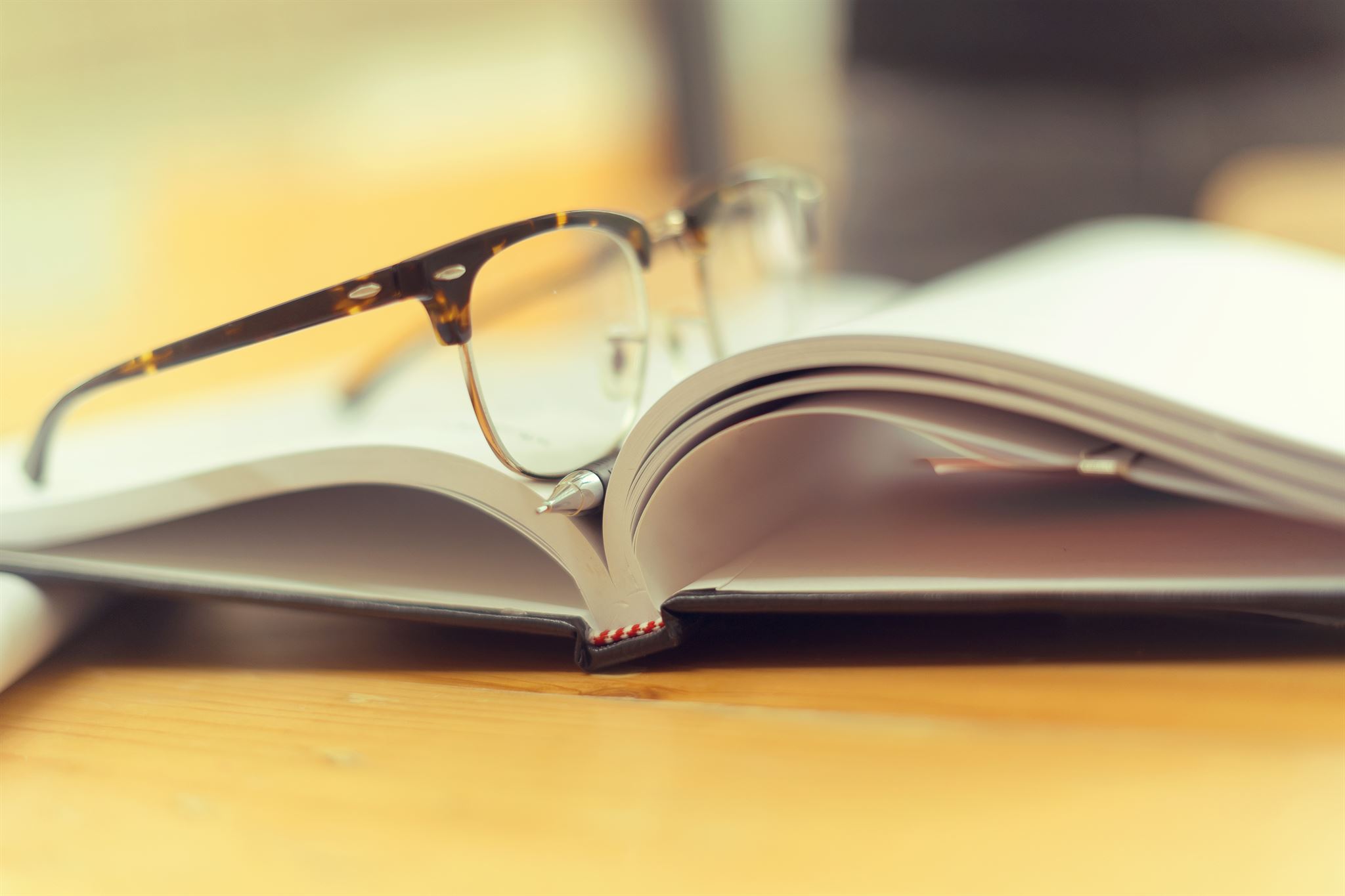 An-open-book-and-on-top-are-eyeglasses-and-pen